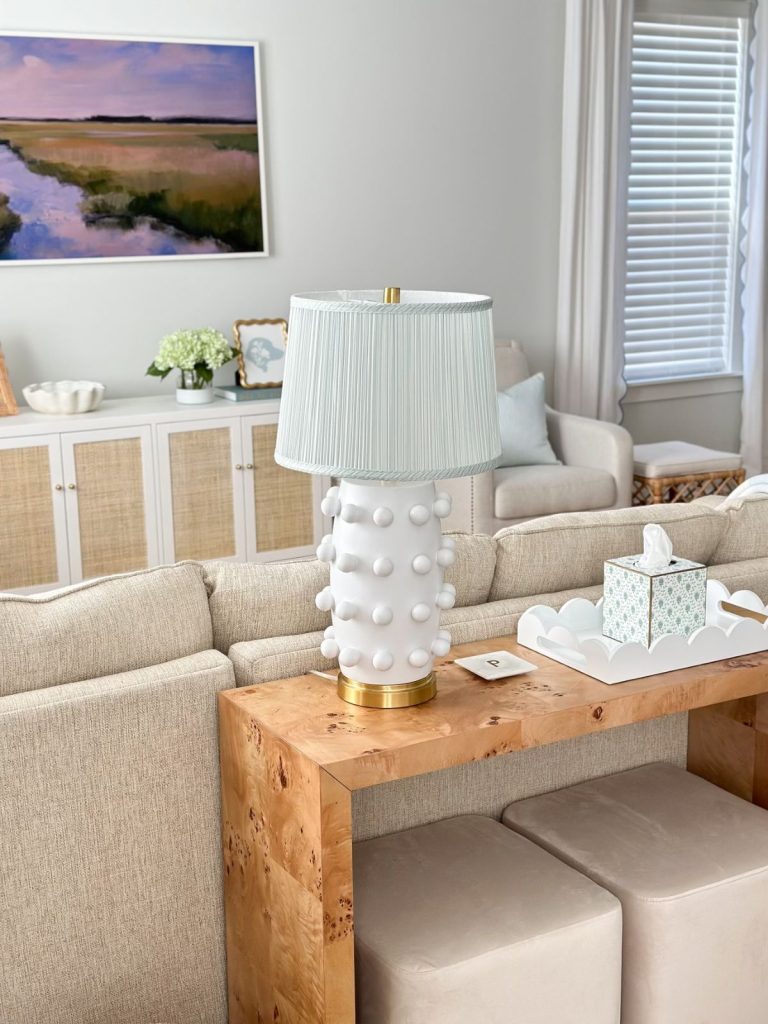 a white lamp with a pleated lampshade sitting on a console table