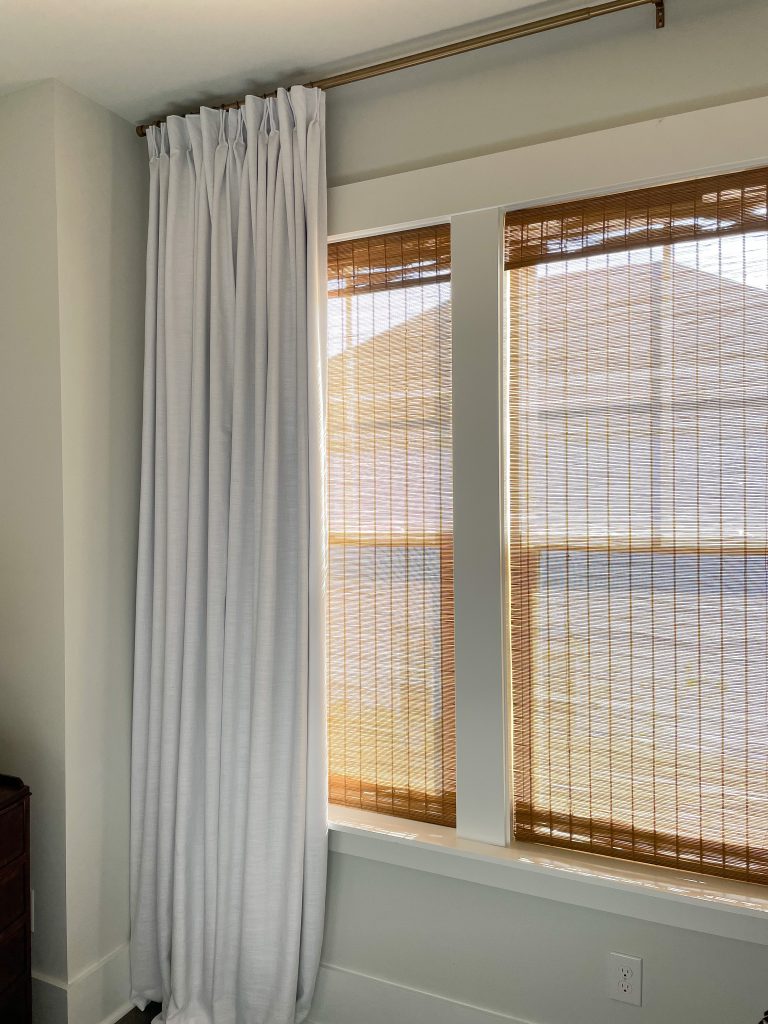bamboo Roman shades with white pinch pleat curtains